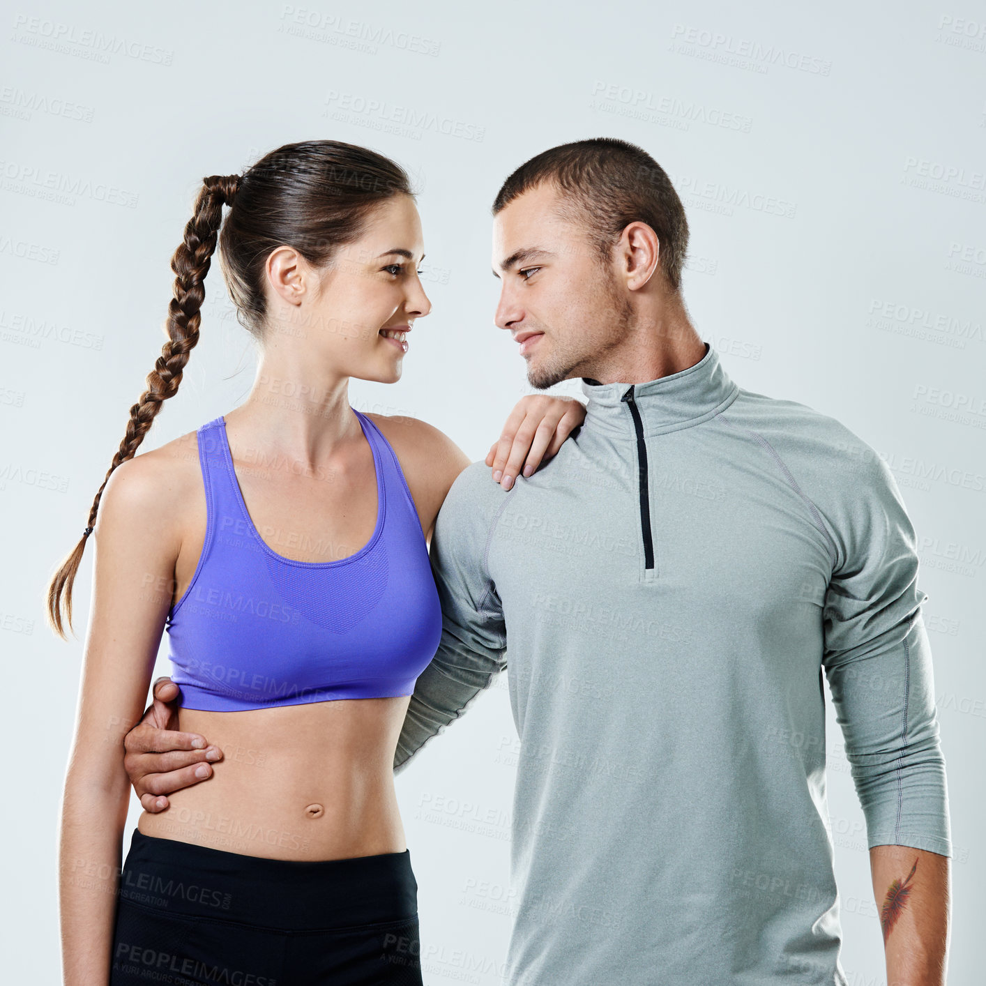 Buy stock photo Happy couple, fitness and hug with love for exercise, training or workout together on a studio background. Young, man and woman with smile, sportswear or support for relationship, health and wellness