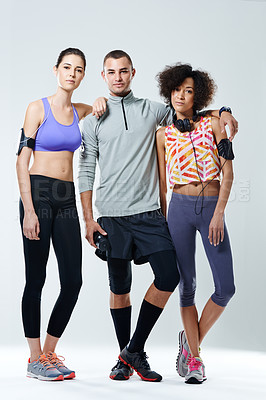 Buy stock photo Portrait of three young adults looking serious in gymwear against a grey background