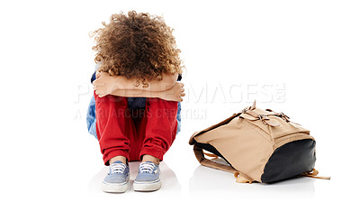 Buy stock photo Studio shot of a little boy with his head buried in his knees sitting next to his schoolbag against a white background
