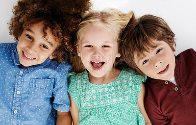 Buy stock photo Studio shot of a group of young friends lying on the floor together against a white background