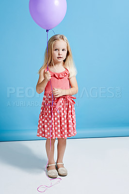 Buy stock photo Shot of a cute little girl holding a balloon over a blue background