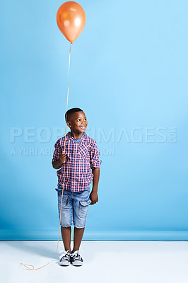 Buy stock photo Shot of a young boy holding a balloon over a blue background