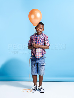 Buy stock photo Shot of a young boy holding a balloon over a blue background