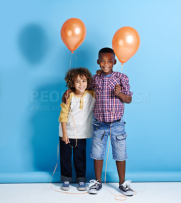 Buy stock photo Portrait of two little boys holding their balloons over a blue background