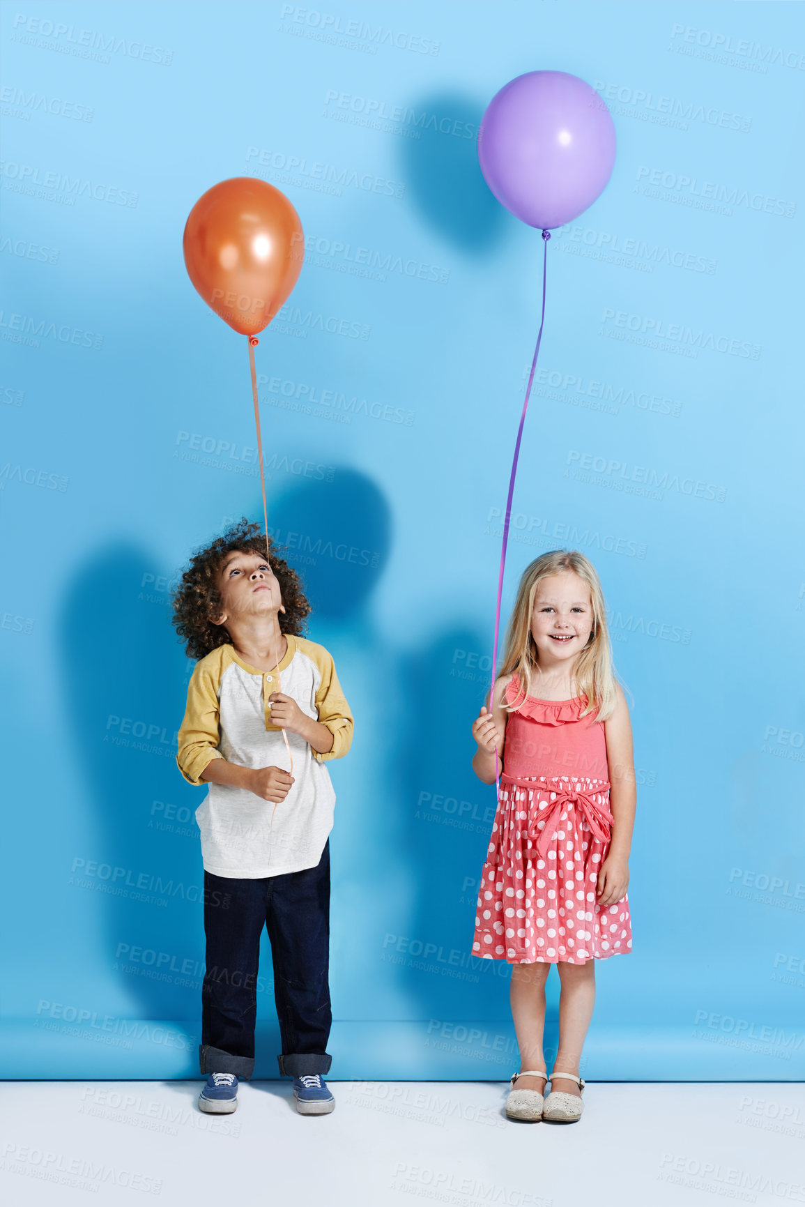 Buy stock photo A cute little girl and boy standing in a studio holding a balloon