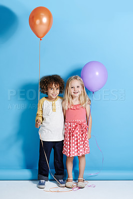 Buy stock photo Portrait of a cute little girl and boy holding a balloon over a blue background