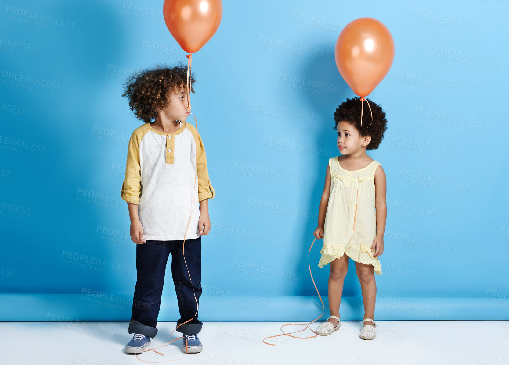 Buy stock photo Shot of a little girl and boy holding a balloon over a blue background