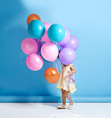 Buy stock photo Shot of a cute little girl standing behind a bunch of balloons