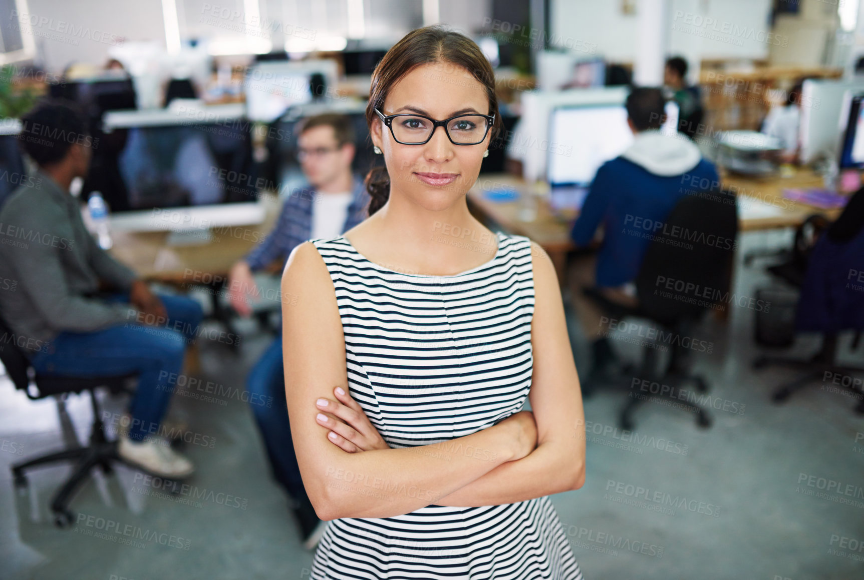 Buy stock photo Portrait of a young woman standing in an office with designers in the background