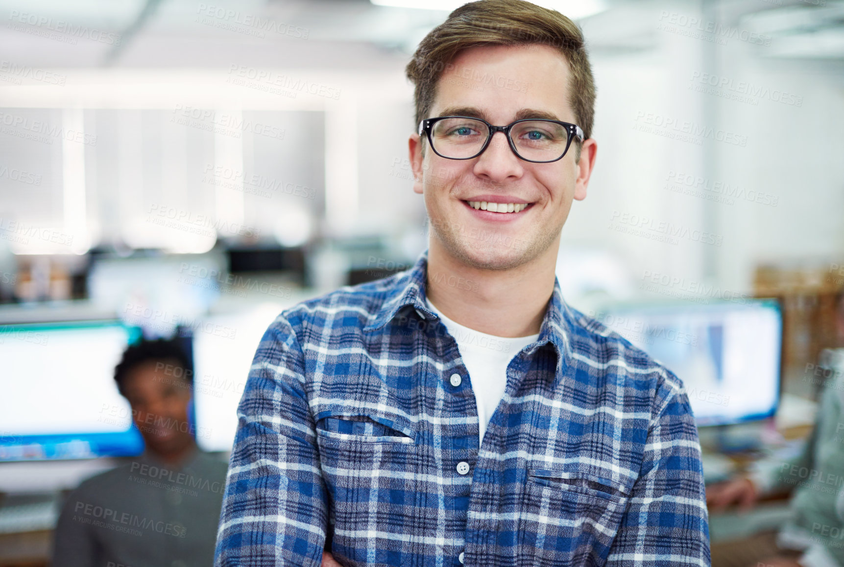 Buy stock photo Portrait of a young man standing in an office with designers in the background