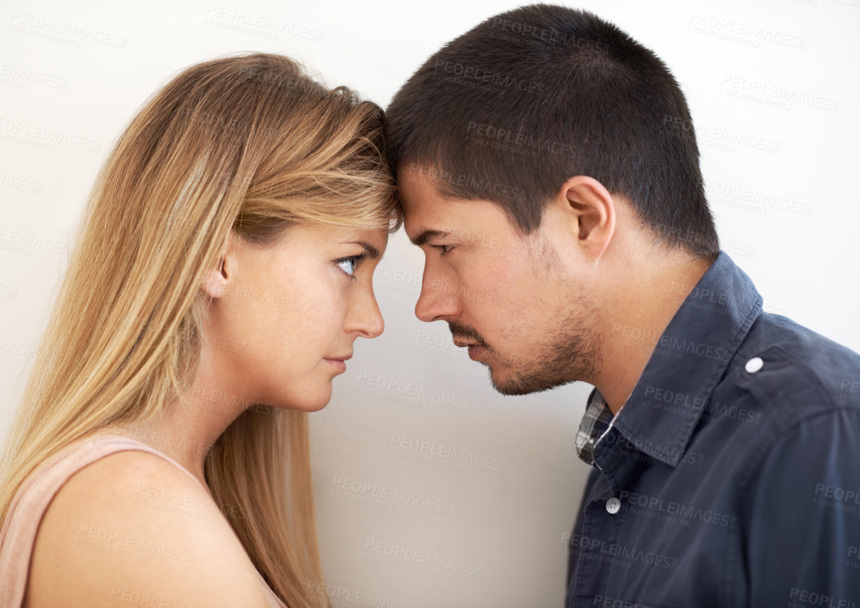 Buy stock photo Serious young couple looking intently at one another