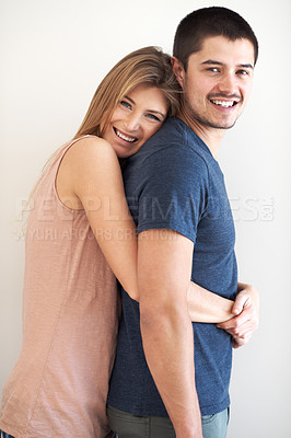 Buy stock photo Portrait, hug and couple in studio happy, bonding and having fun against a wall background. Face, smile and woman embracing man with care, romance and love while enjoying their relationship together