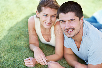 Buy stock photo An attractive young couple lying on the grass together and smiling