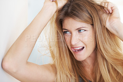 Buy stock photo Cropped head and shoulders shot of a young woman with her hands in her hair and a crazed expression