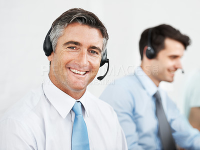 Buy stock photo Male customer service agents at work while wearing headsets