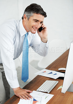 Buy stock photo Mature businessman standing at his desk and making a phone call