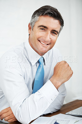 Buy stock photo Handsome mature businessman sitting at his desk with a smile