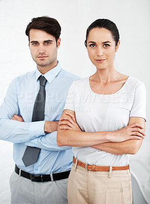 Buy stock photo Two serious young business colleagues standing together with their arms folded