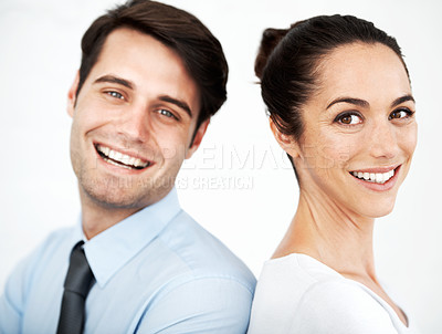Buy stock photo Two young business colleagues standing together while smiling agianst a white background
