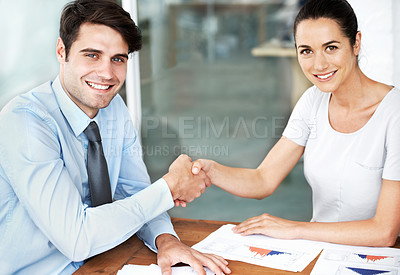 Buy stock photo Young businesspeople shaking hands while seated at a desk