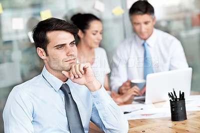 Buy stock photo Thoughtful young businessman sitting in a group meeting