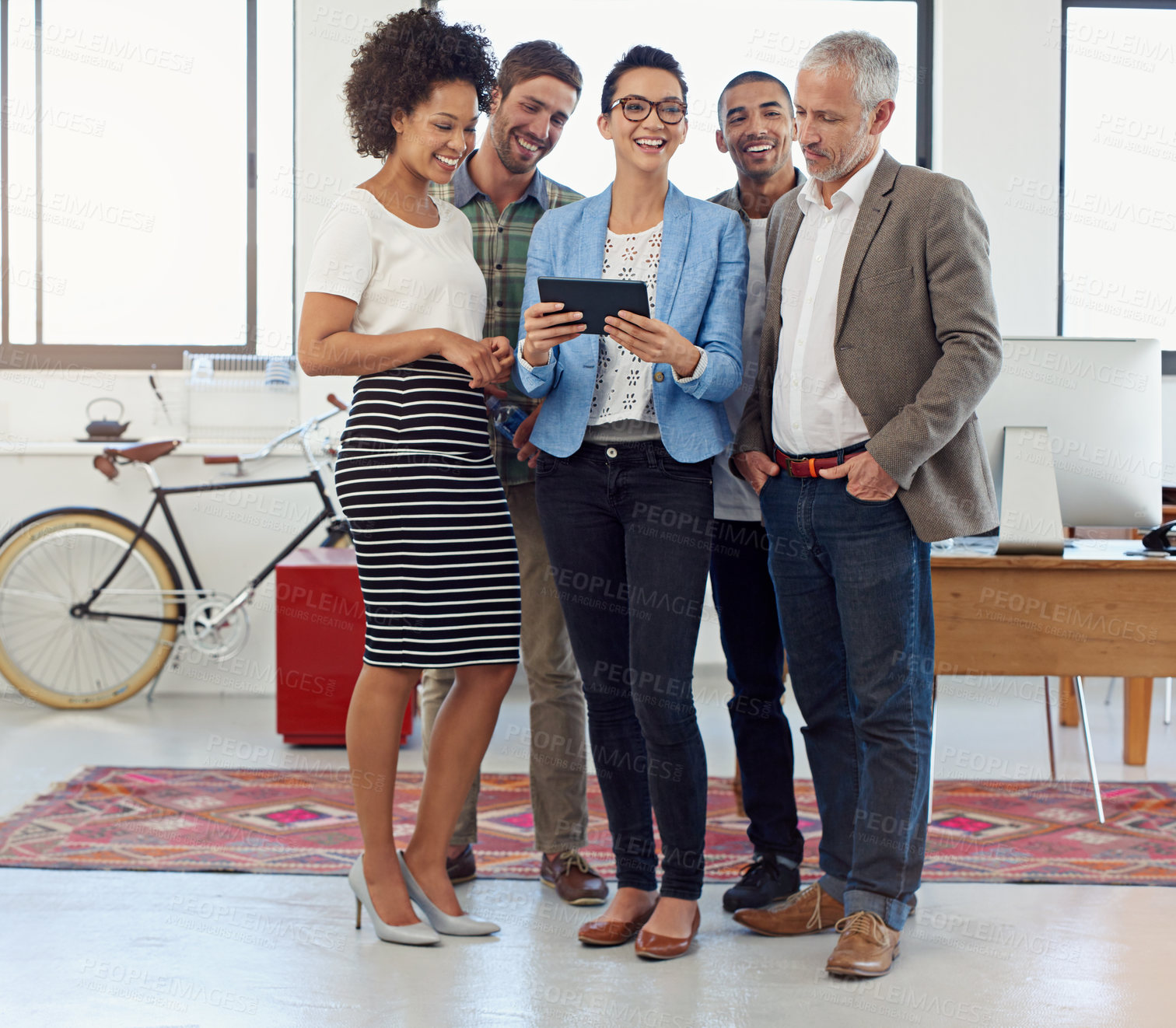 Buy stock photo Shot of a group of coworkers looking at a digital tablet in an office