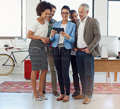 Buy stock photo Shot of a group of coworkers looking at a digital tablet in an office