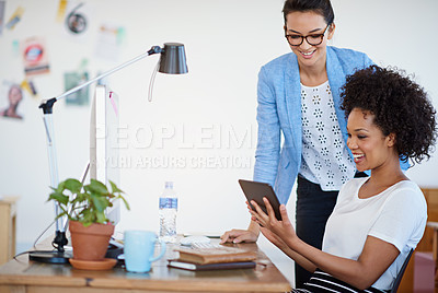 Buy stock photo Shot of two coworkers using a digital tablet together in the office