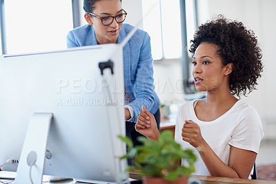 Buy stock photo Shot of two colleagues having a discussion at a computer in the office