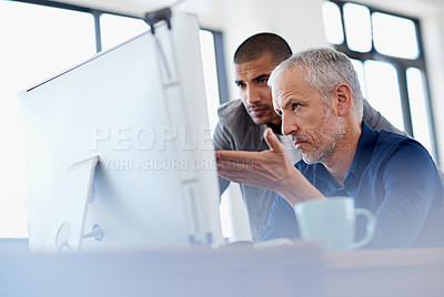 Buy stock photo Shot of two colleagues having a discussion at a computer in the office