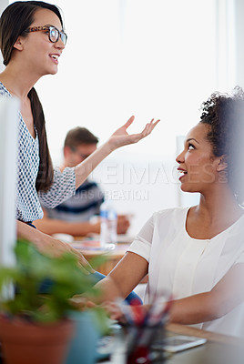 Buy stock photo Shot of two colleagues having a conversation at their desk in an office