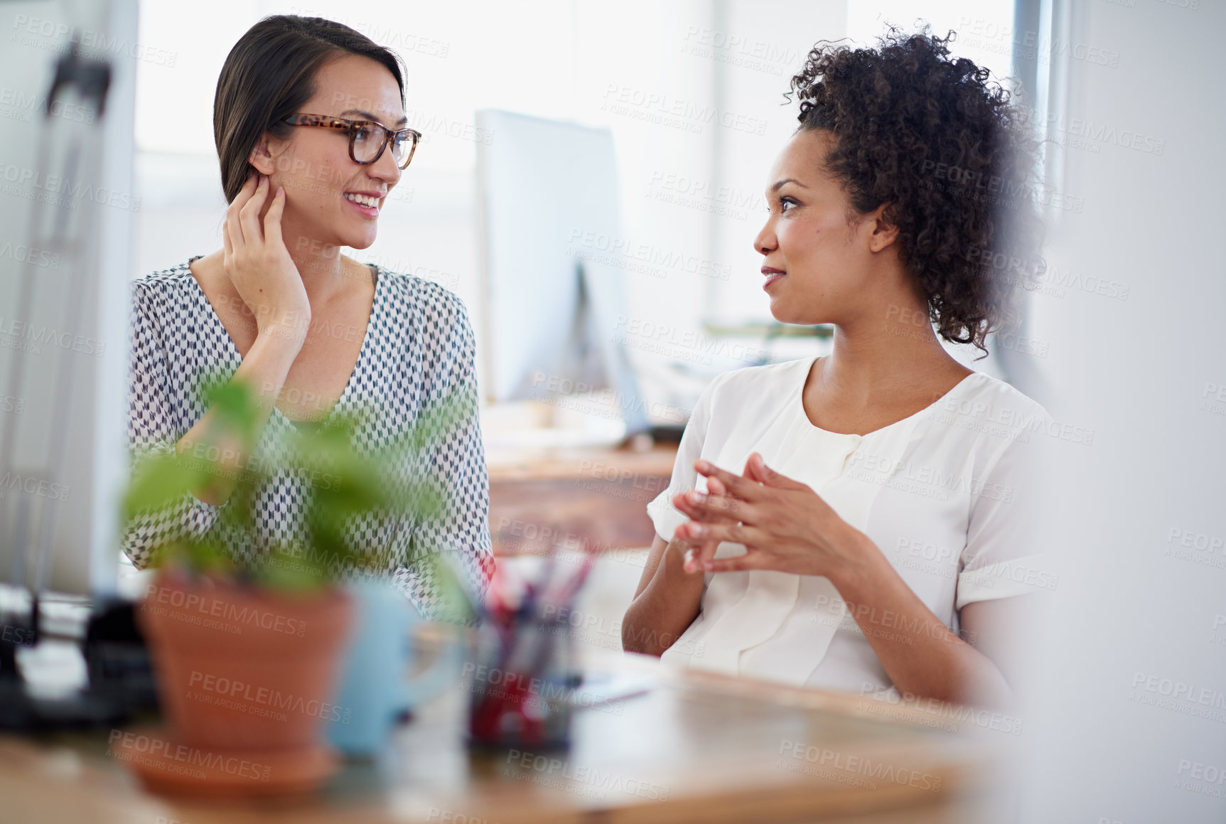 Buy stock photo Shot of two colleagues having a conversation at their desk in an office