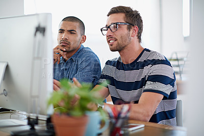 Buy stock photo Shot of two colleagues having a discussion at their computer in the office