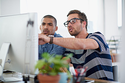 Buy stock photo Shot of two colleagues having a discussion at their computer in the office