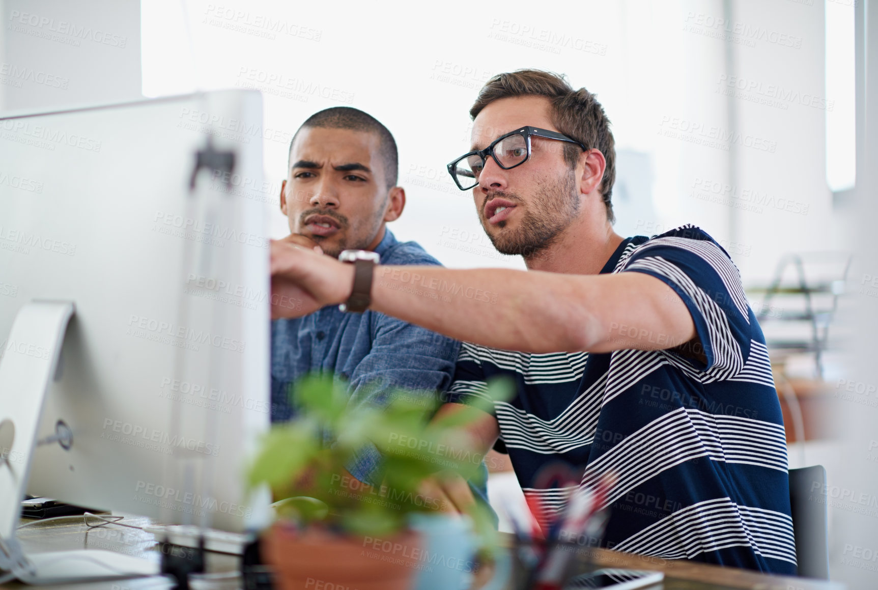 Buy stock photo Shot of two colleagues having a discussion at their computer in the office