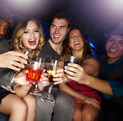 Buy stock photo An excited group of friends celebrating and drinking champagne together