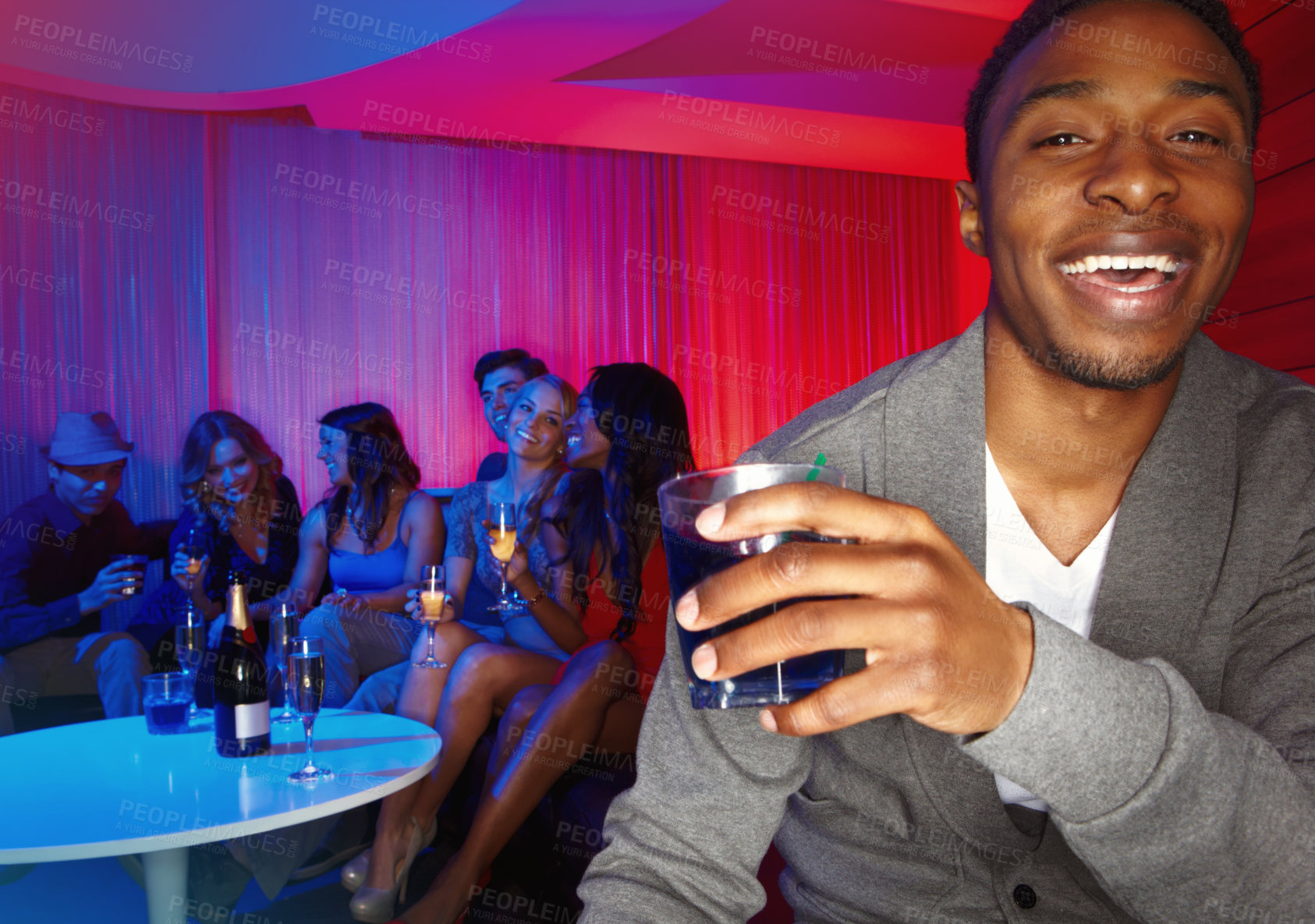 Buy stock photo A handsome african american man enjoying drinks while out clubbing with his friends