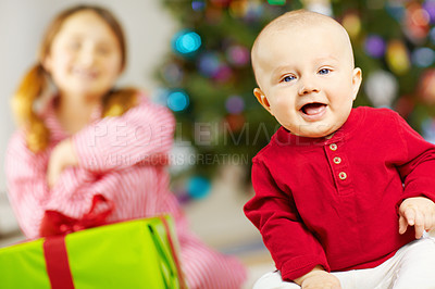 Buy stock photo Baby, portrait and gift by Christmas tree in home, playful or happy for surprise in living room. Infant, child and present in box with ribbons, smile or festive celebration at family house in Germany