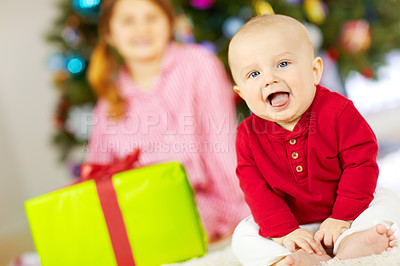 Buy stock photo An excited baby at christmas time sitting next to a wrapped present