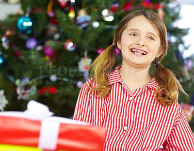 Buy stock photo Girl, smile and present by Christmas tree in morning, pajamas and happy for surprise in living room. Child, gift and package with ribbons, excited and Xmas for festive celebration in family home