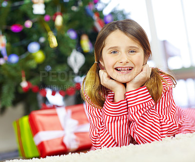 Buy stock photo Girl, portrait and happy by Christmas tree in morning, pajamas and excited for festive party in living room. Child, gift box and smile on carpet, celebration and xmas at family home in Australia