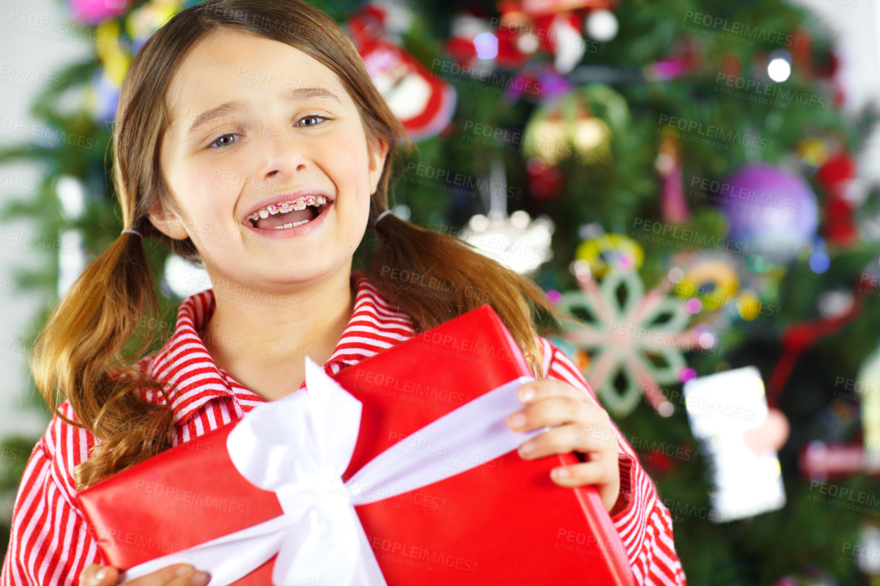 Buy stock photo Christmas, gift box and excited child with present ready to celebrate holiday, vacation and festival tradition. Happiness, festive celebration and face of girl with braces with gift by Christmas tree