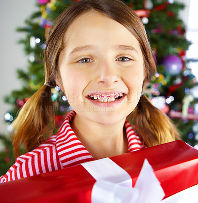 Buy stock photo Portrait of a girl with braces on christmas day holding her unwrapped present