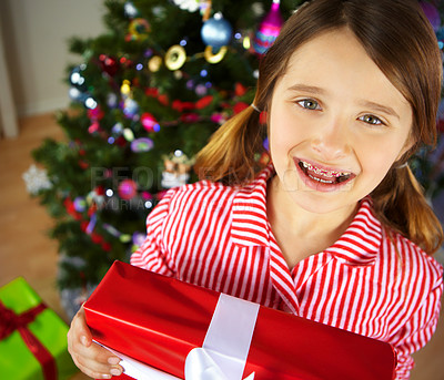 Buy stock photo Christmas, girl and gift for celebration, excited and festive season. Portrait, braces and female child enjoy presents,  happiness and vacation for Xmas, break and holiday to relax, joy and in lounge