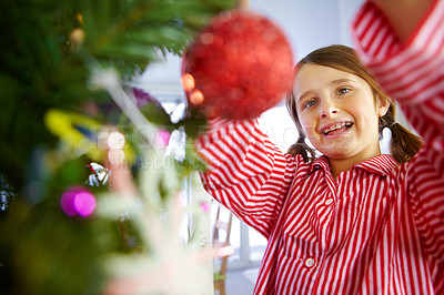 Buy stock photo A girl with braces on putting decorations on her christmas tree whilst in her pajamas