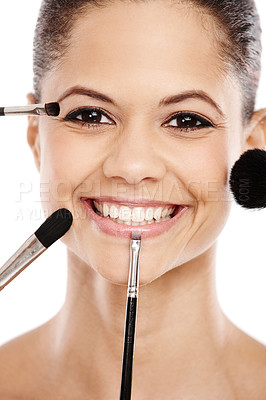 Buy stock photo Concept image of a young woman with an assortment of brushes applying makeup to her face