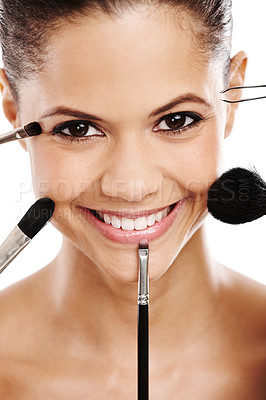 Buy stock photo Concept image of a young woman with an assortment of brushes applying makeup to her face