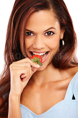 Buy stock photo Beautiful young woman biting into a fresh strawberry with a smile
