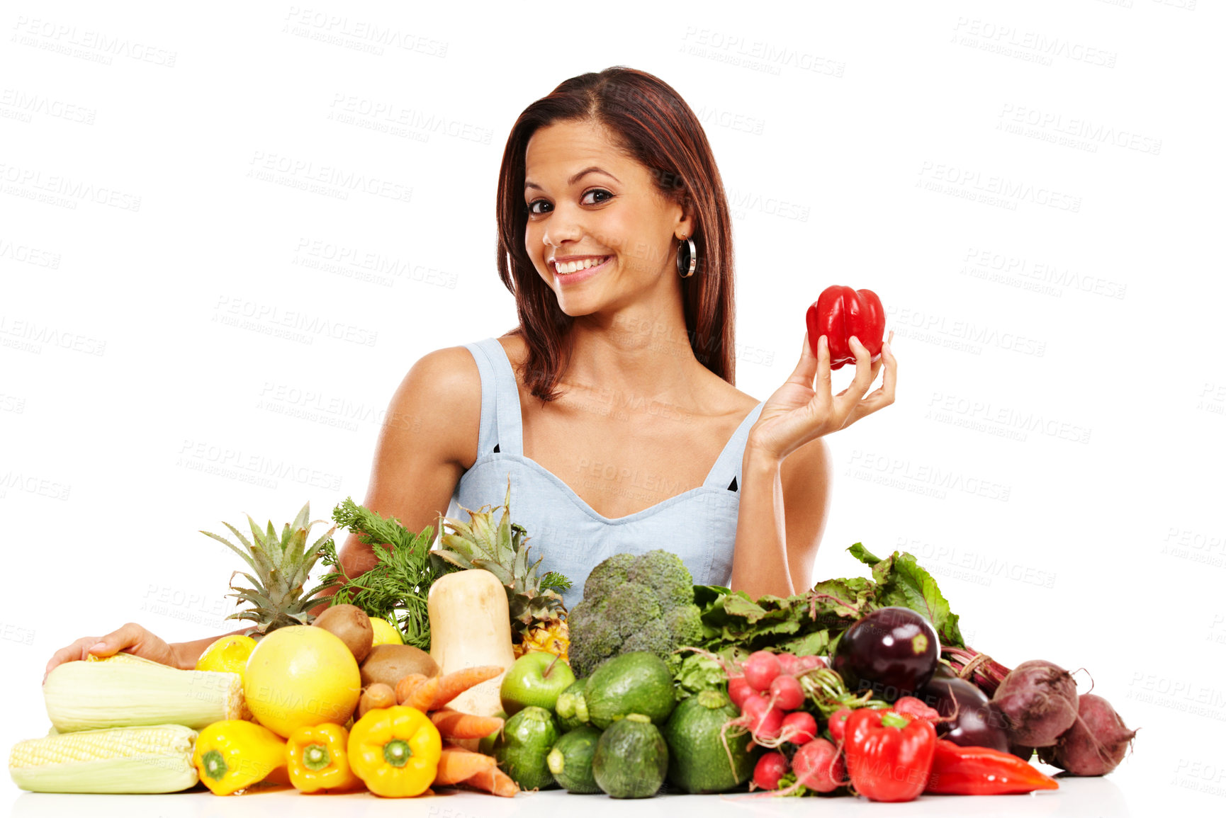 Buy stock photo Attractive young woman smiling while holding a red pepper alongside a pile of fresh vegetables against a white background