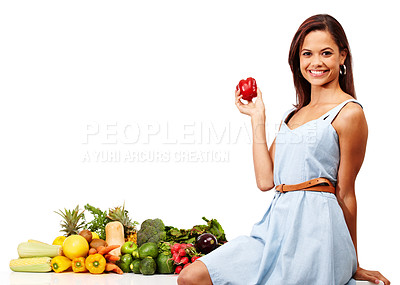 Buy stock photo Attractive young woman smiling while holding a red pepper alongside a pile of fresh vegetables against a white background